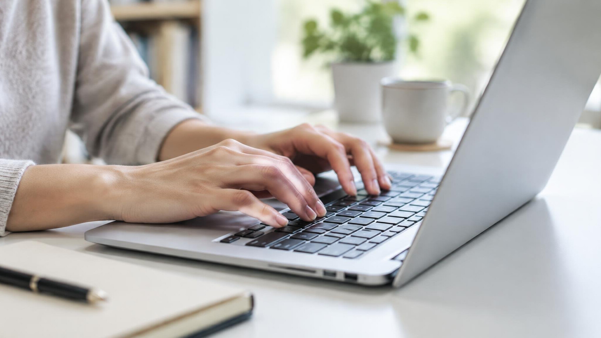 Hands typing on a laptop keyboard